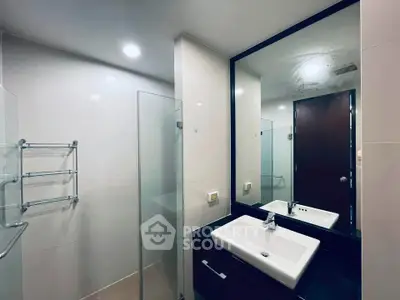Modern bathroom with sleek design, featuring a large mirror and stylish sink.