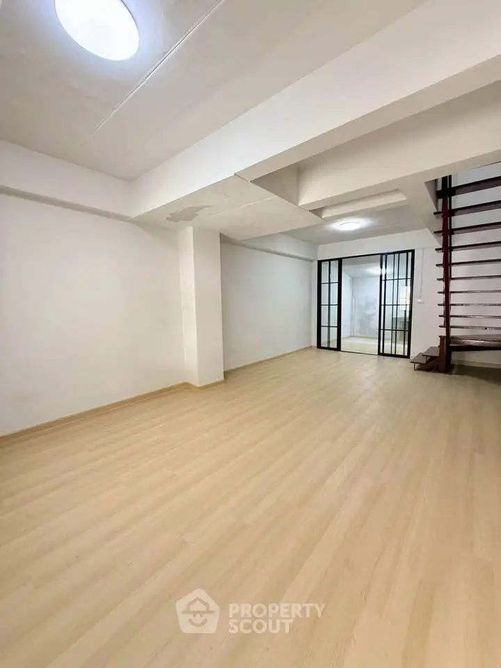 Spacious modern interior with wooden flooring and glass partition, ideal for versatile living space.