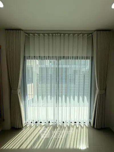 Elegant window with sheer curtains in a modern apartment, offering natural light and privacy.