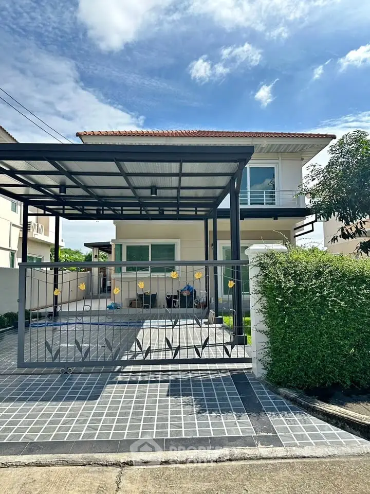 Charming two-story house with gated driveway and lush greenery, perfect for family living.