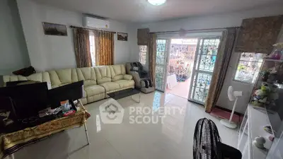 Spacious living room with large windows and balcony access, featuring modern decor and ample natural light.