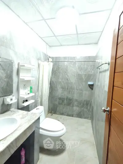 Modern bathroom with marble countertop and tiled walls in a sleek design.