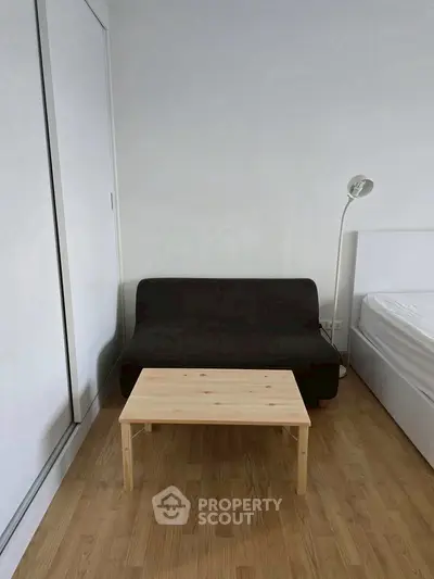 Minimalist bedroom with compact sofa and wooden table, ideal for modern living.