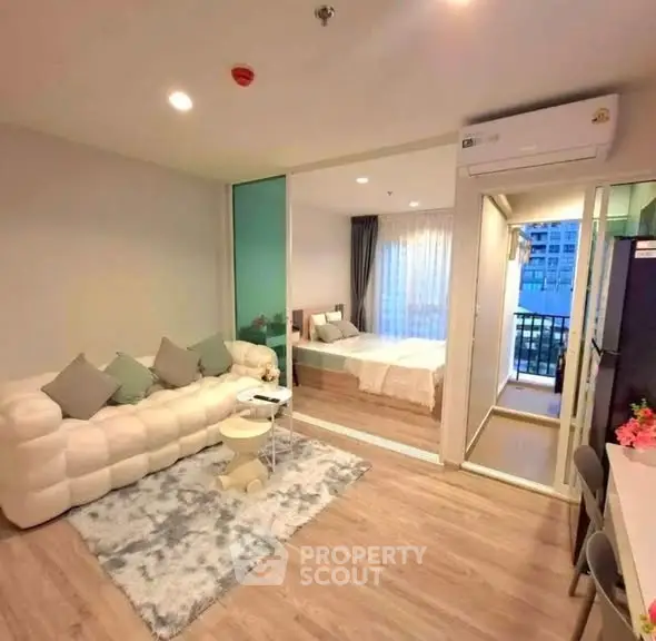 Modern open-plan living room with cozy bedroom and balcony view in stylish apartment.