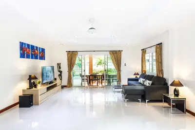 Spacious living room with modern decor and large windows opening to a garden view.