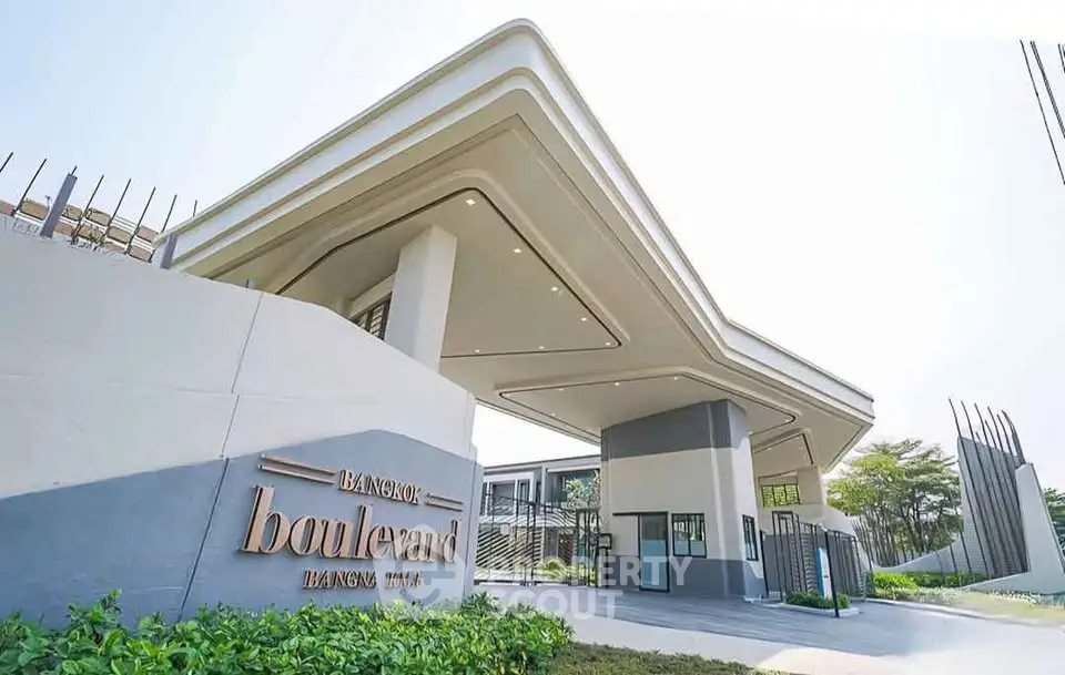 Modern entrance of Bangkok Boulevard showcasing sleek architecture and lush greenery.