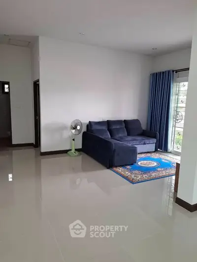 Spacious living room with blue sofa and elegant rug, perfect for relaxation.