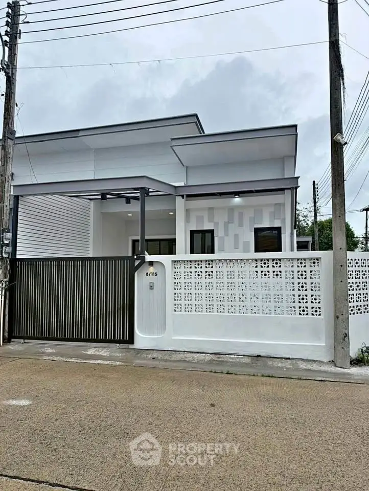 Modern single-story house with sleek design and gated entrance in a suburban neighborhood.