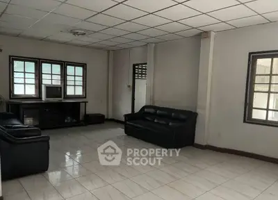 Spacious living room with tiled flooring and ample natural light, featuring comfortable seating and a classic TV setup.