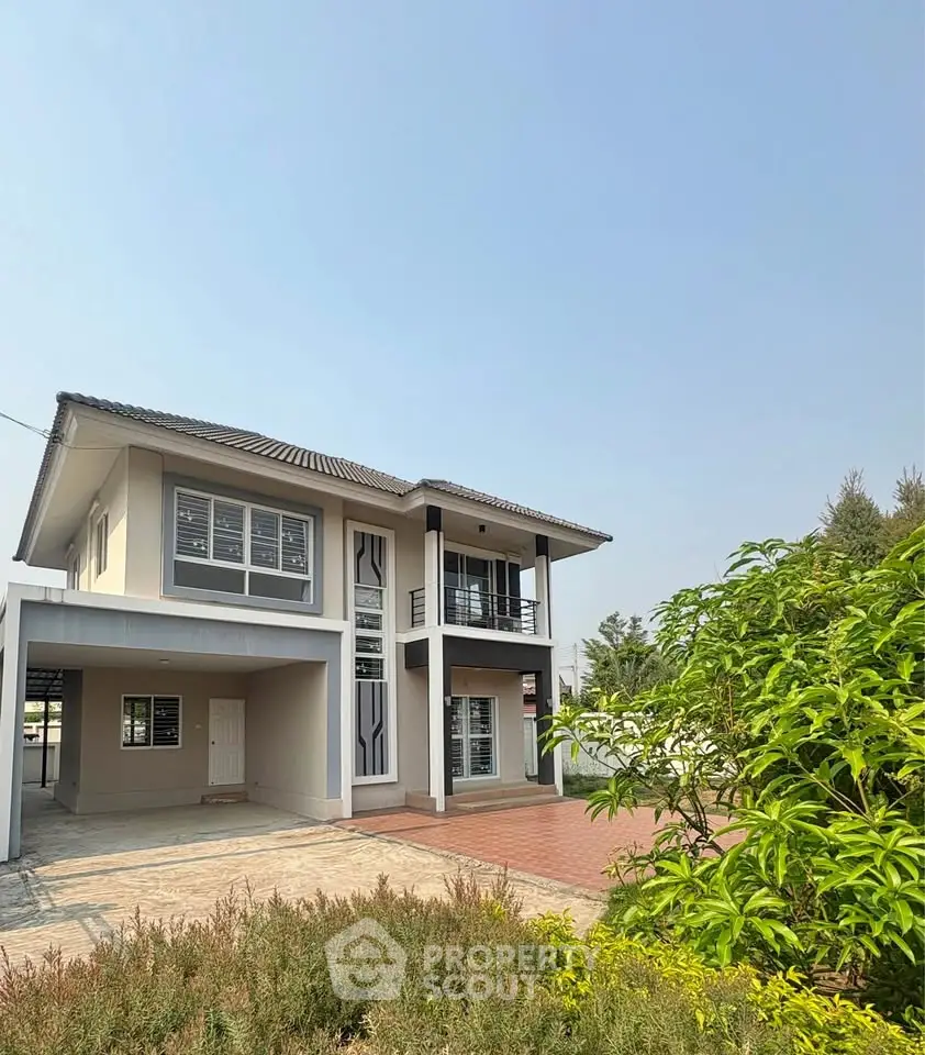 Modern two-story house with balcony and spacious driveway under clear blue sky.