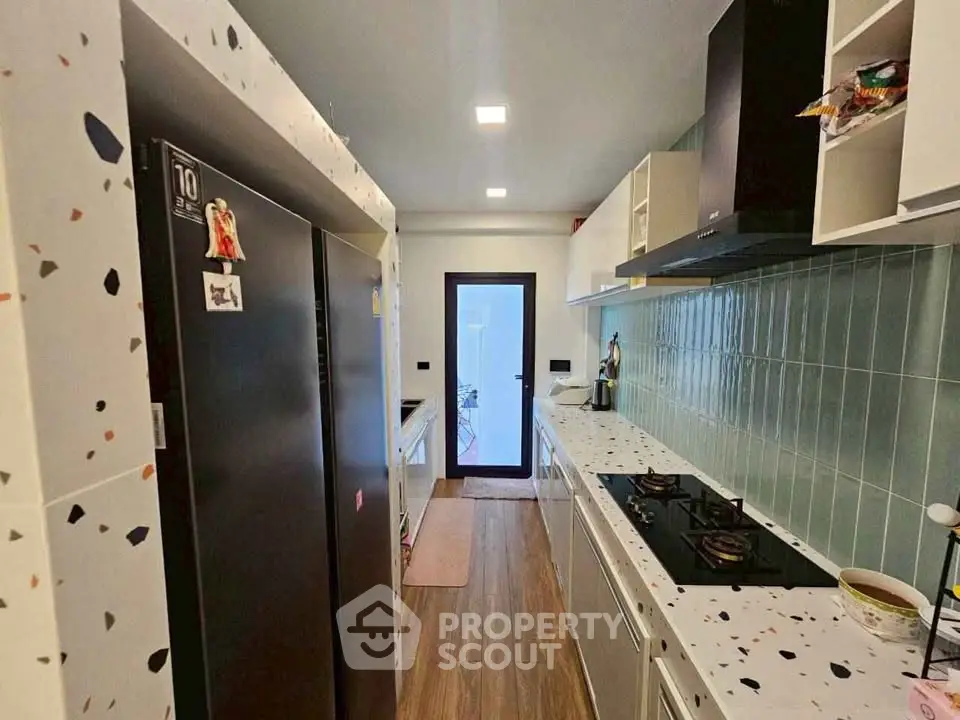 Modern kitchen with terrazzo countertops and gas stove, featuring sleek cabinetry and stylish backsplash.