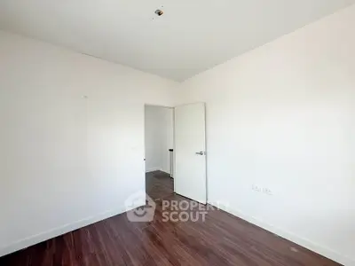Spacious empty room with wooden flooring and white walls, perfect for customization.