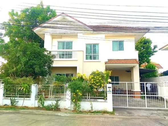 Charming two-story house with lush garden and gated entrance in a serene neighborhood.