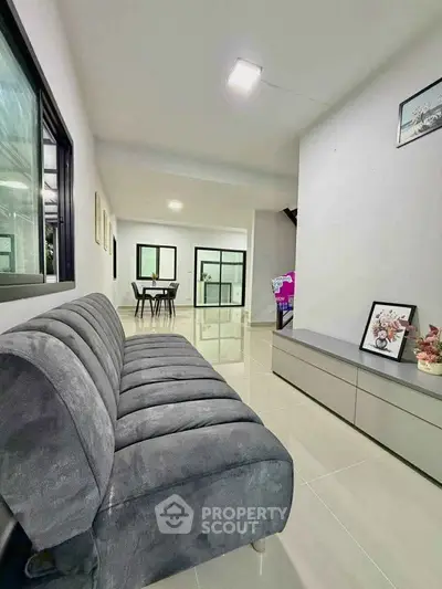 Modern living room with sleek sofa and minimalist decor, showcasing open layout and bright ambiance.