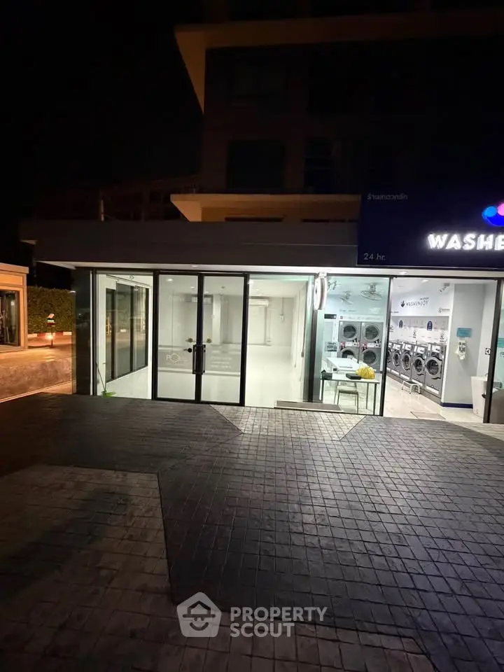 Modern laundromat exterior with glass doors and bright lighting, open 24 hours for convenience.