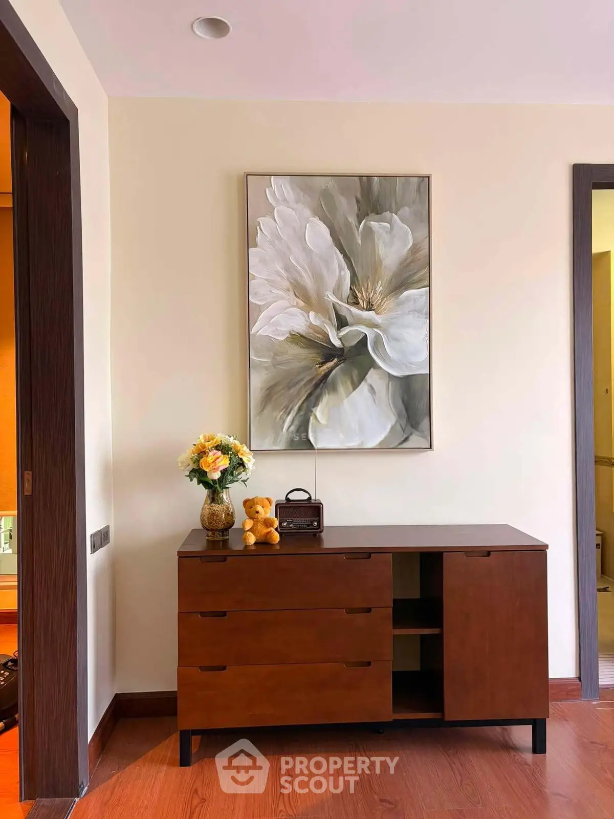 Elegant interior with wooden dresser and floral artwork, showcasing modern home decor.