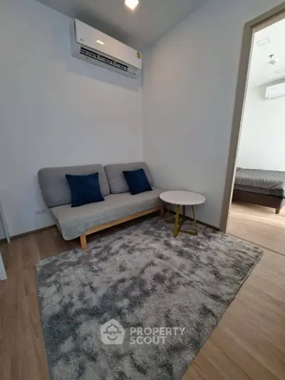 Cozy living room with modern sofa, plush rug, and air conditioning in a stylish apartment.