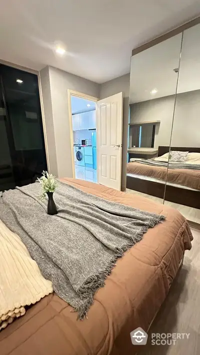 Cozy bedroom with mirrored wardrobe and view into modern kitchen