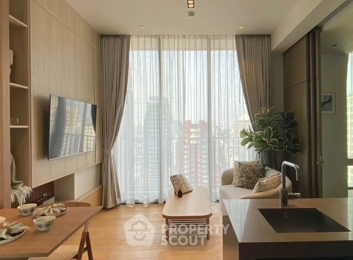 Modern living room with large windows and city view, featuring stylish furniture and open kitchen layout.