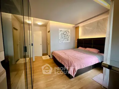 Modern bedroom with stylish decor and wooden flooring, featuring a cozy bed and elegant lighting.