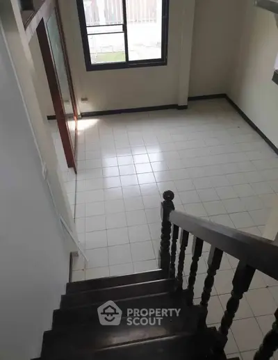 Spacious interior with tiled flooring and wooden staircase, perfect for modern living.