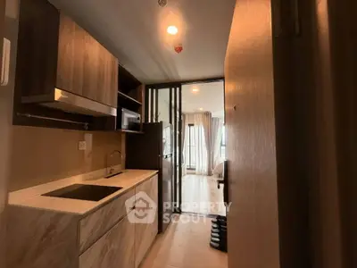 Modern apartment entrance with compact kitchen and view into cozy living area.