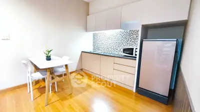 Modern kitchen with sleek cabinetry and dining area in cozy apartment.