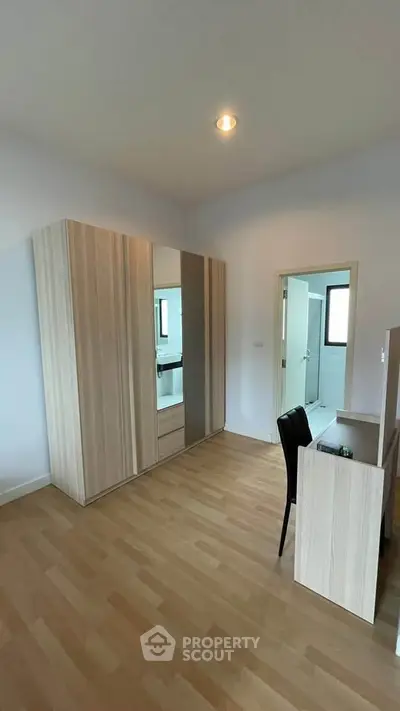 Spacious bedroom with wooden flooring and modern wardrobe, ideal for comfortable living.