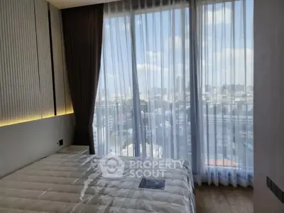 Modern bedroom with floor-to-ceiling windows offering stunning city views.