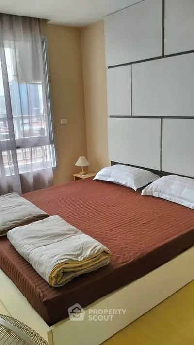 Modern bedroom with large bed and stylish decor in a high-rise apartment.