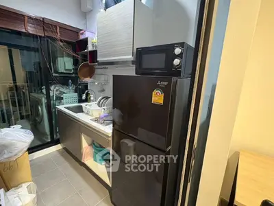 Modern kitchen with sleek black fridge and microwave, featuring a compact layout and stylish design.