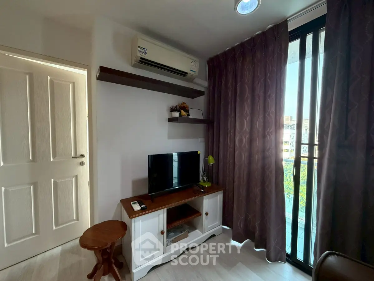 Cozy living room with TV, air conditioning, and balcony view in modern apartment.