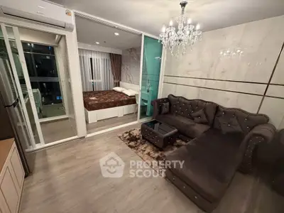 Luxurious living room with elegant chandelier and plush sofa, adjacent to a cozy bedroom.