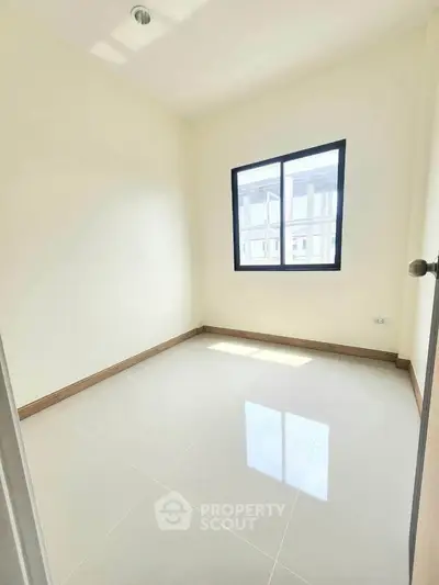 Bright empty room with large window and glossy tiled floor in modern apartment.
