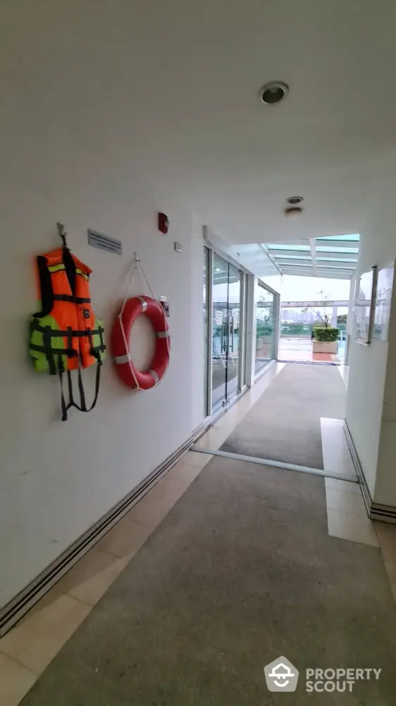 Modern building entrance with safety equipment and glass doors leading to outdoor area.