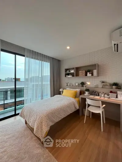 Modern bedroom with stylish decor and balcony view, featuring cozy bed and workspace.