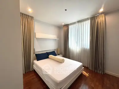 Cozy bedroom with elegant curtains and wooden flooring, perfect for relaxation.