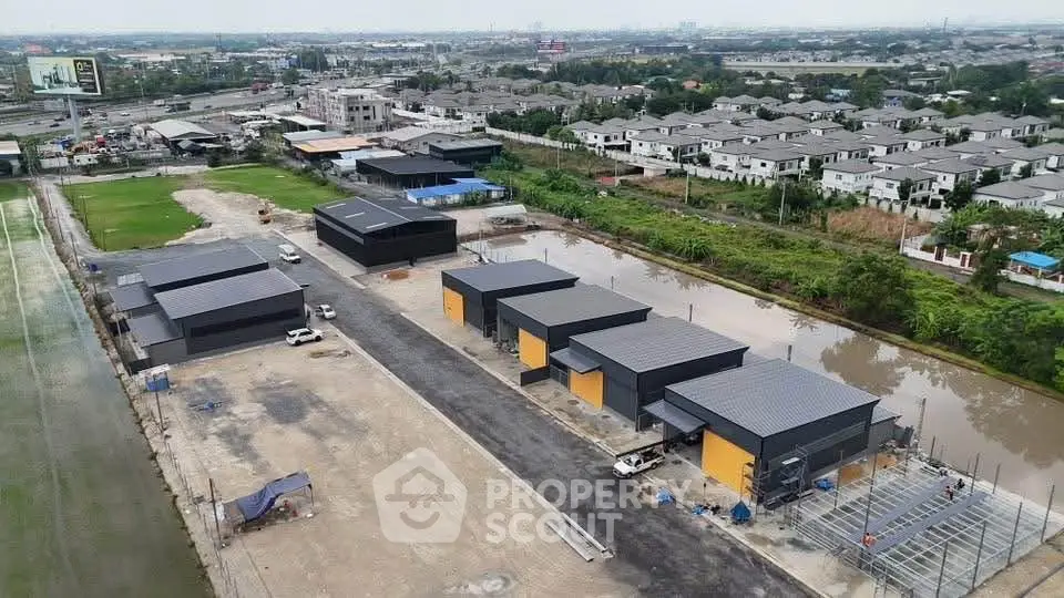 Aerial view of modern industrial buildings in a suburban area with surrounding greenery.