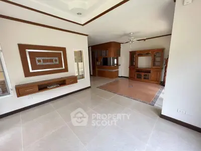 Spacious living room with elegant wooden furniture and tiled flooring in a modern home.