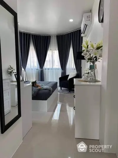 Modern bedroom with elegant decor and large windows, featuring sleek furniture and stylish curtains.