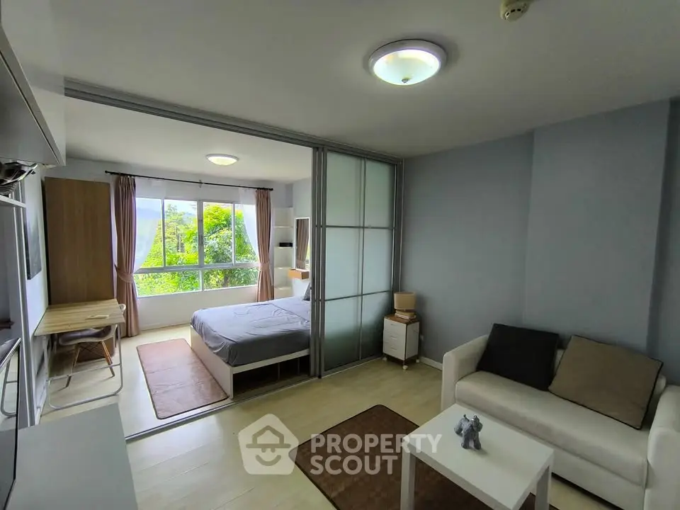 Modern studio apartment with sliding glass doors and scenic window view