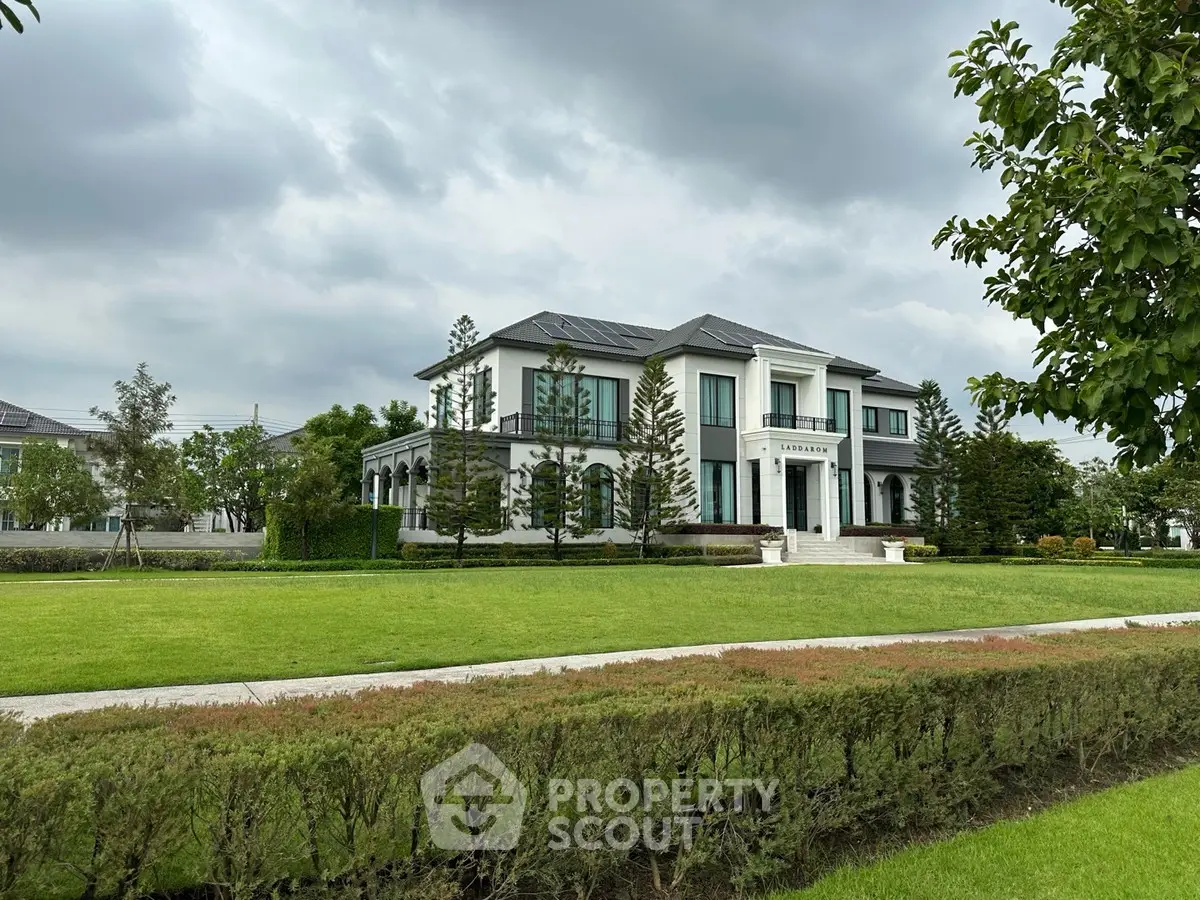 Luxurious modern mansion with manicured lawn and elegant architecture under cloudy skies.