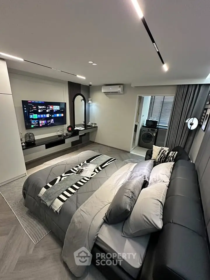 Modern bedroom with sleek design, featuring a wall-mounted TV and stylish decor.