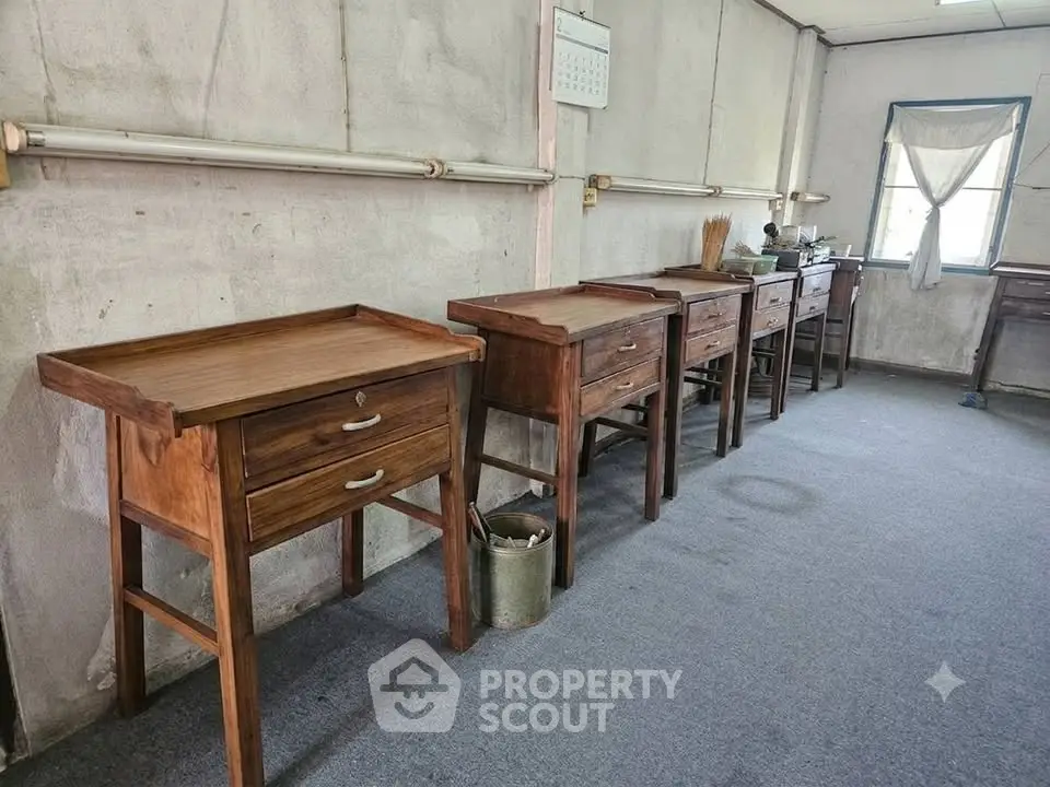 Spacious room with wooden desks and natural light, ideal for creative workspace or study area.