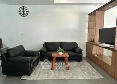 Modern living room with black leather sofas and wooden entertainment unit