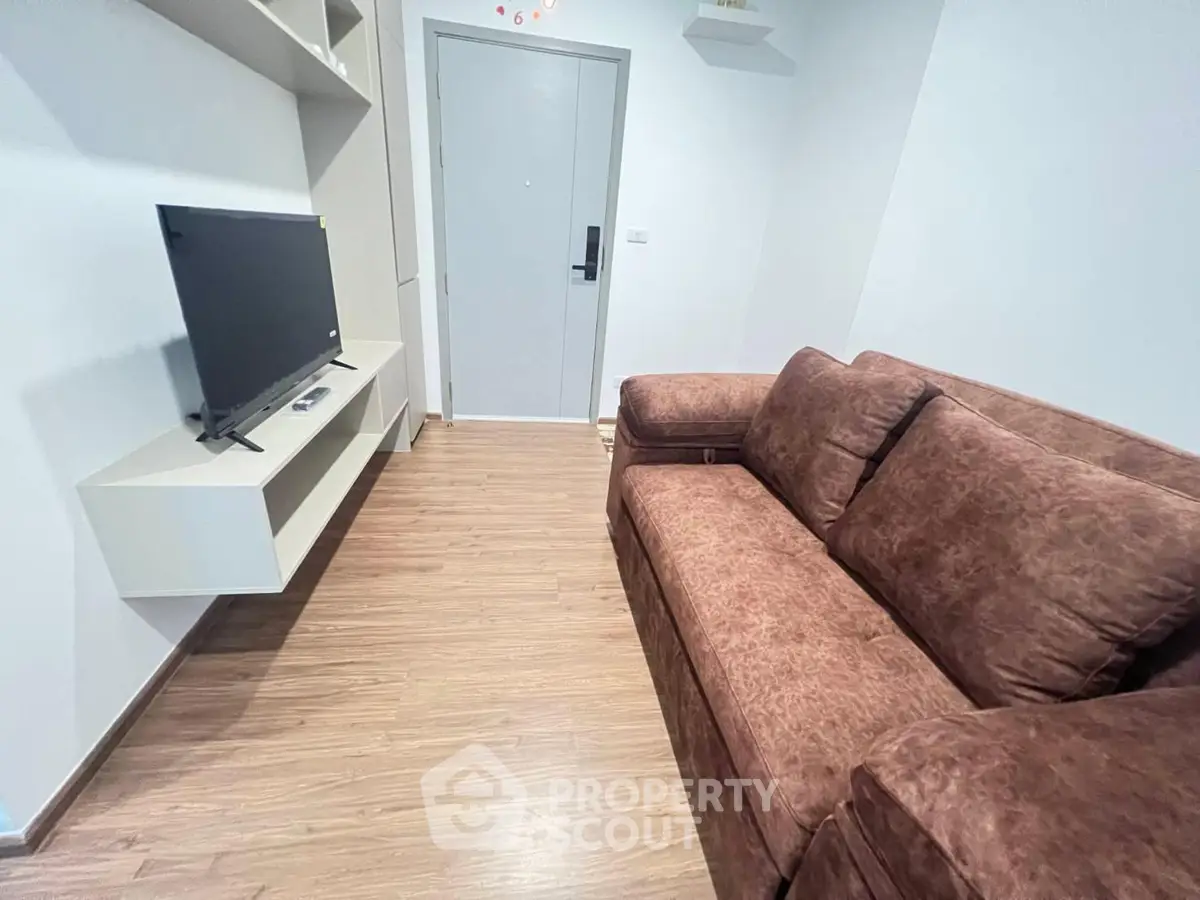 Cozy living room with brown sofa and wall-mounted TV in modern apartment.
