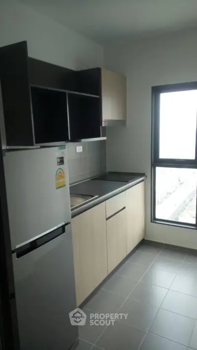 Modern kitchen with sleek cabinetry and large window offering natural light.