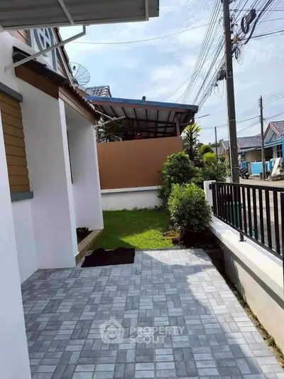 Charming residential exterior with tiled patio and lush garden, perfect for outdoor relaxation.
