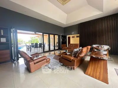 Luxurious modern living room with leather sofas and large windows opening to a patio.