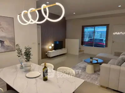 Modern living room with stylish lighting and elegant decor, featuring a cozy seating area and a sleek dining table.